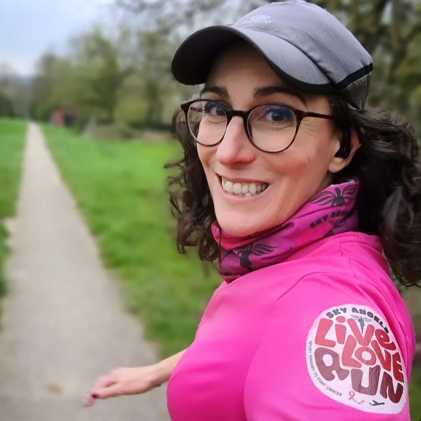 Cécile en train de courir dans le désert, sac à dos et casquette, sourire.